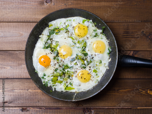 Fried eggs in a frying pan on a plank background. Delicious breakfast. View from above