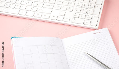 Pink pastel woman office desk with keyboard and diary.Top view with copy space