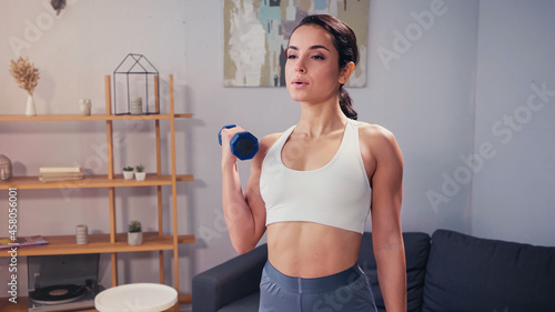 Pretty woman working out with dumbbell at home