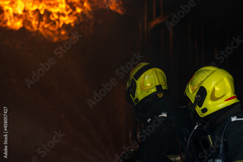 Fireman,Firefighters fighting a fire and spraying high pressure water to fire.