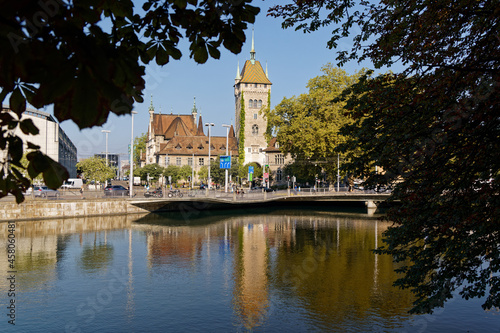National Landes Museum Zurich, view limmatquai to Walche Bridge on an autumn morning, building and spire between trees against blue sky, wide angle shot