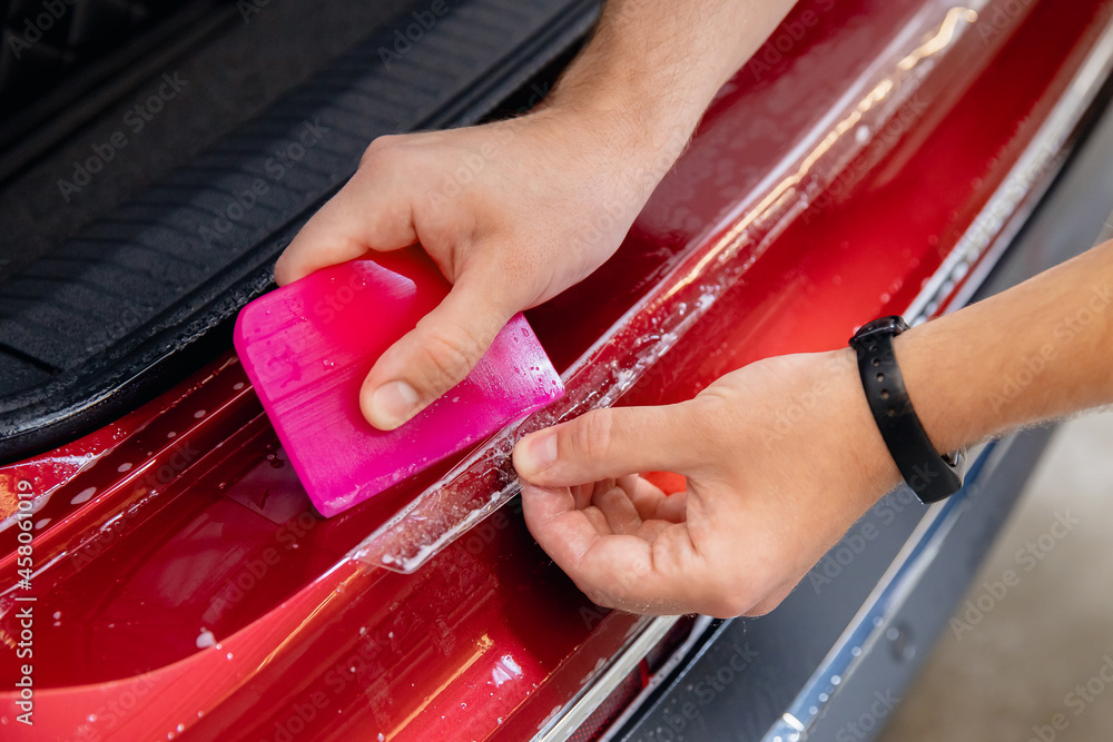 Master man installs vinyl film protect trunk loading area car body