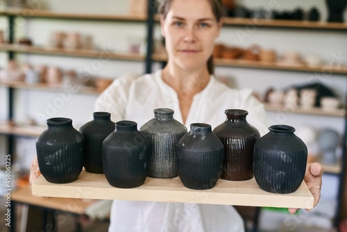 woman artisan ceramist holding small black handmade clay vases in her hands