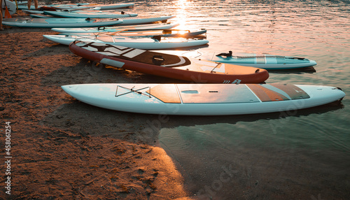 Close up of stand up SUP paddle board on lake or sea with blue water lilies, paddling in summer time at a sunset. Summer family vacation