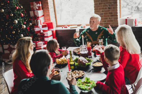 Photo portrait of full family listening to grandpa saying toast drinking champagne on christmas