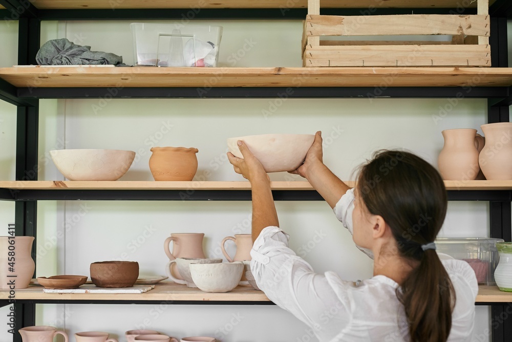 woman artisan ceramist puts on a rack a bowl of handmade clay woman artisan ceramist puts on a rack a bowl of handmade clay