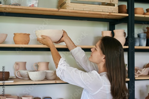woman artisan ceramist puts on a rack a bowl of handmade clay