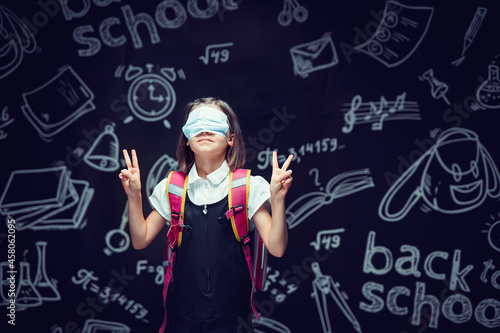 Schoolgirl in fun in medical mask on eyes gesturing V signs. Virus protection. Victory for Covid-19  © zamuruev