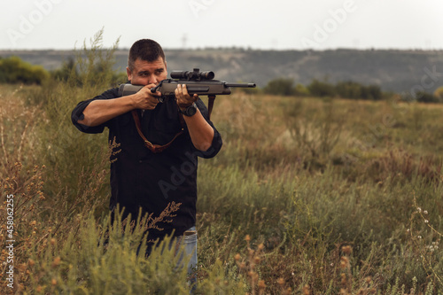 Portrait of a shooter with a rifle. European shoots a rifle with a optics sight