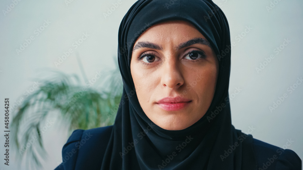 close up of young muslim businesswoman in hijab looking at camera in office close up of young muslim businesswoman in hijab looking at camera in office