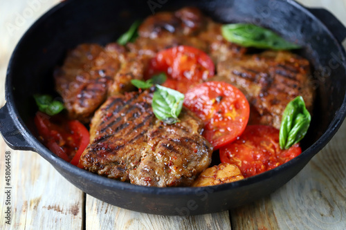 Steaks with basil, vegetables and spices. Grilled steaks in a pan.