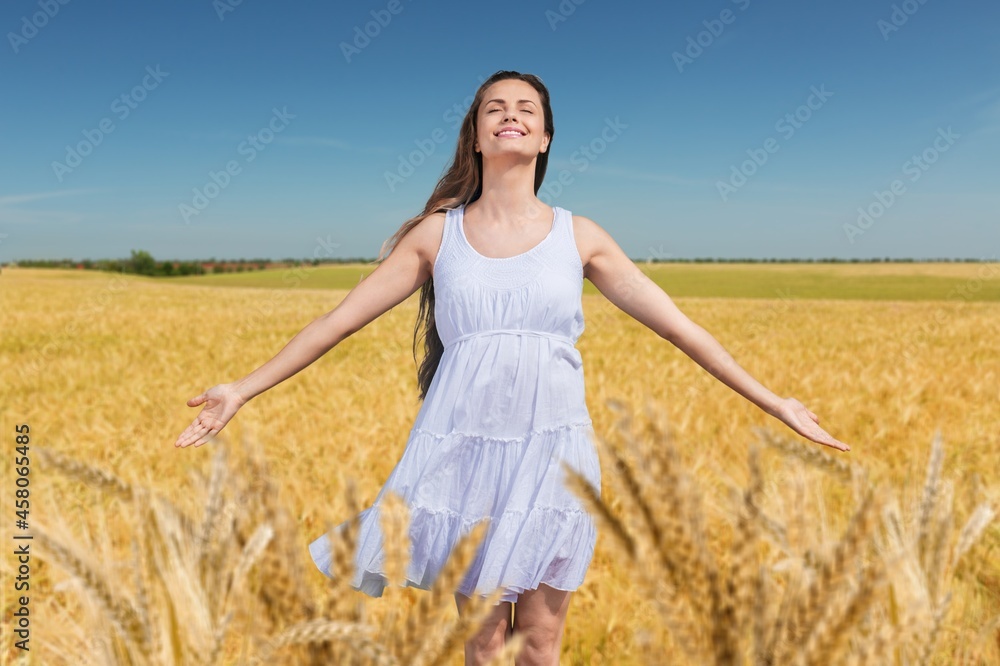 Naklejka premium Happy young beautiful woman in a wheat field.