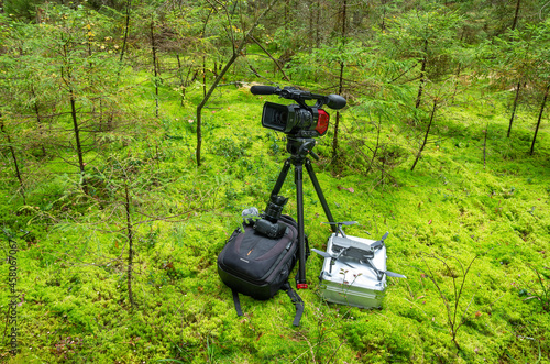 A video camera, a camera and a copter on a background of green moss. A set of equipment for video shooting. photo