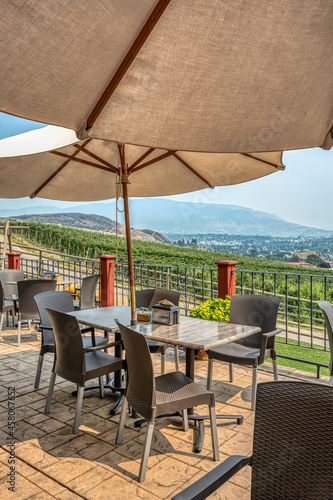 Street cafe tables under satin umbrellas with Okanagan valley overview