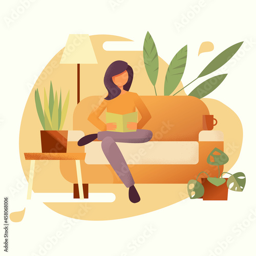 The woman is sitting on the couch and reading a book.
