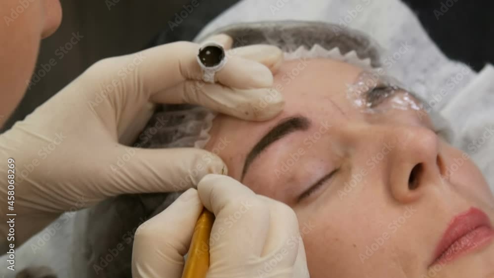 Manual technique of Microblading, master applies a special dark pigment with special pen for coloring eyebrows, permanent makeup, tattooing in beauty parlor Manual technique of Microblading, master applies a special dark pigment with special pen for coloring eyebrows, permanent makeup, tattooing in beauty parlor
