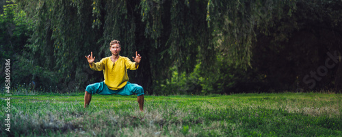 Man doing horse stance exercise. Qigong practice in the nature.