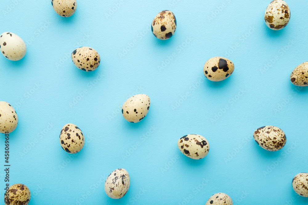 Quail eggs on light blue table background. Pastel color. Food pattern. Top down view.