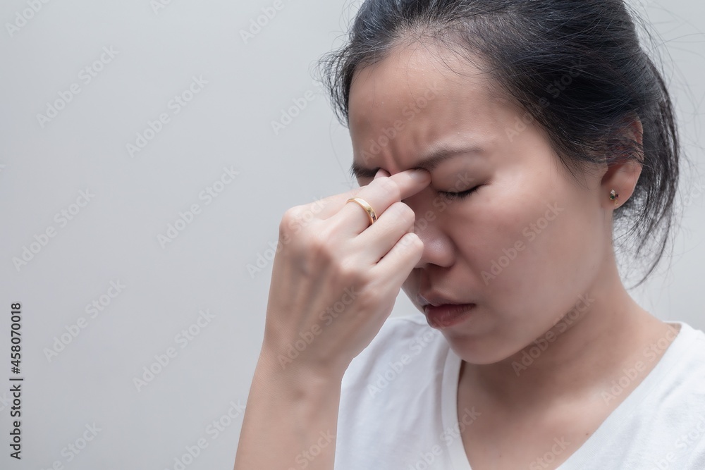 Asian woman with white t-shirt squeezes her eyebrows because headache, flu, COVID 19 or stress. Healthcare concept Asian woman with white t-shirt squeezes her eyebrows because headache, flu, COVID 19 or stress. Healthcare concept