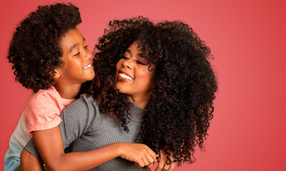 Portrait of young African American mother with toddler son. Red background. Brazilian family.