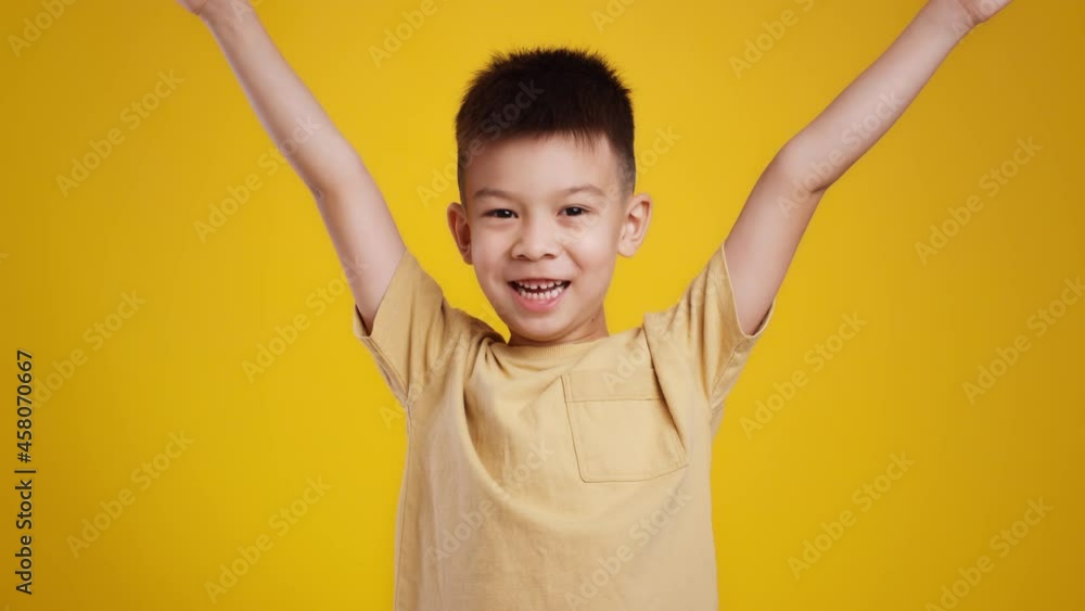 Hooray. Cute little asian boy raising hands up and shouting, enjoying great news or surprise, smiling to camera Hooray. Cute little asian boy raising hands up and shouting, enjoying great news or surprise, smiling to camera
