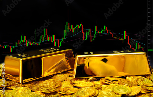 Gold bullion on pile gold coins at trading chart background photo