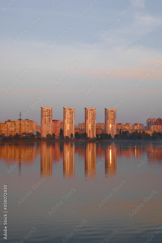 Sunset on the lake, beautiful reflection of the sun and buildings in the water.