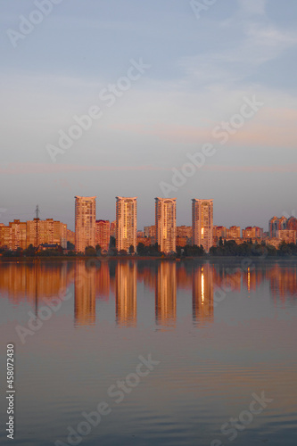 Sunset on the lake, beautiful reflection of the sun and buildings in the water. © mar1sha