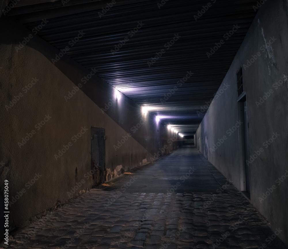 dangerous slums of back street underground tunnel at night with electricity lamps light