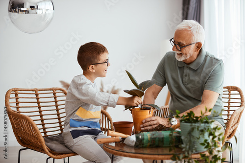 Happy grandfather and grandson enjoy while taking care of plants at home.