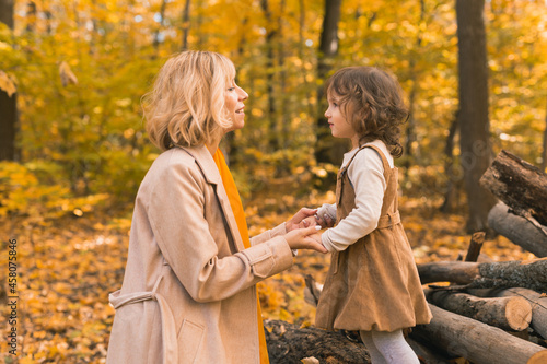 Young mother with her little daughter in an autumn park. Fall season, parenting and children concept. © satura_