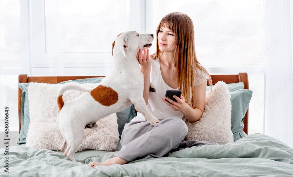 Girl with dog and smartphone in the bed Girl with dog and smartphone in the bed