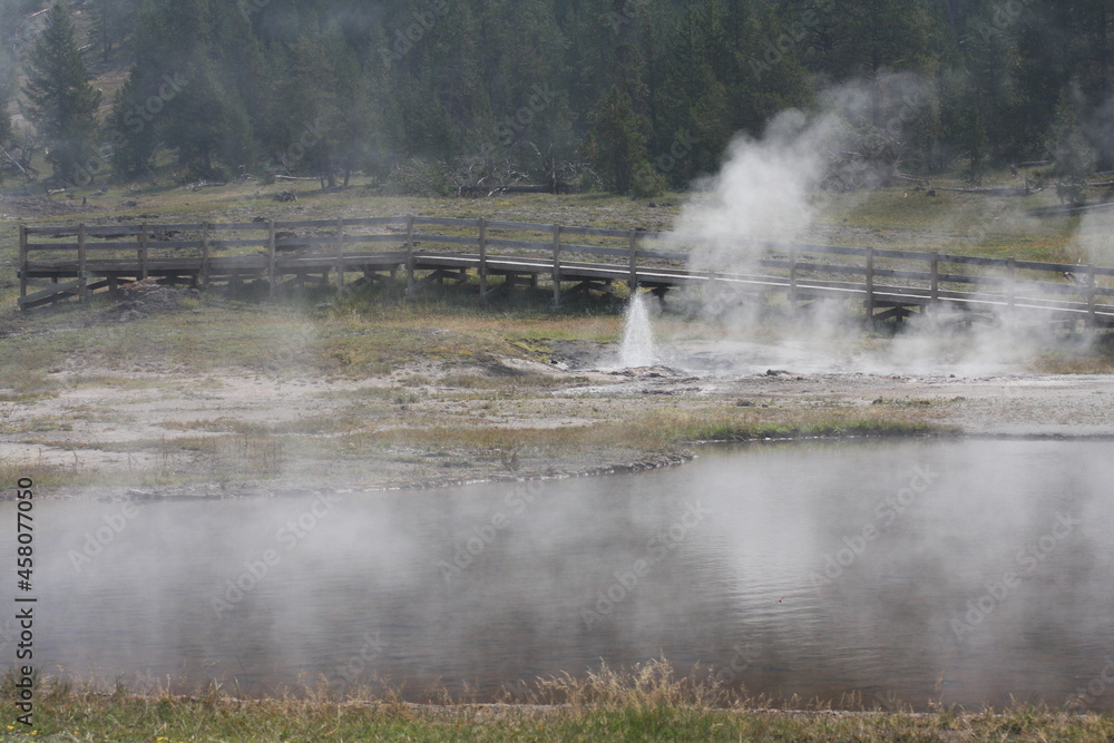 Geyser erupting with forest, lake and bridge Geyser erupting with forest, lake and bridge