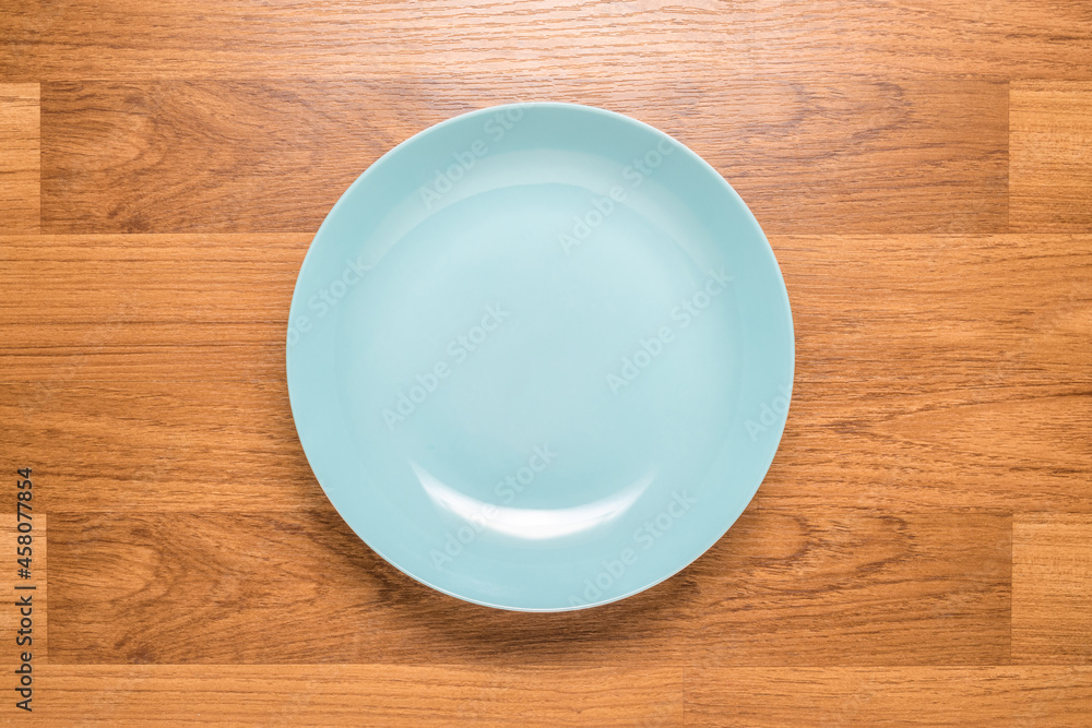 Ceramic empty round dish in turquoise color on wood table, top view Ceramic empty round dish in turquoise color on wood table, top view