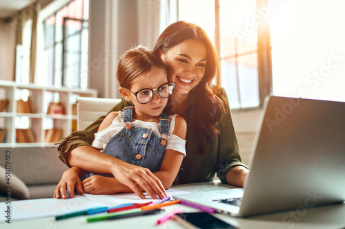 Business woman and mom working with her little daughter at a laptop. Freelance, work from home. photo