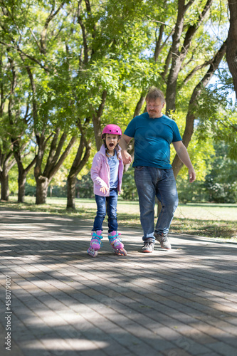 Fototapeta Naklejka Na Ścianę i Meble -  dad teaches daughter to roller skate.