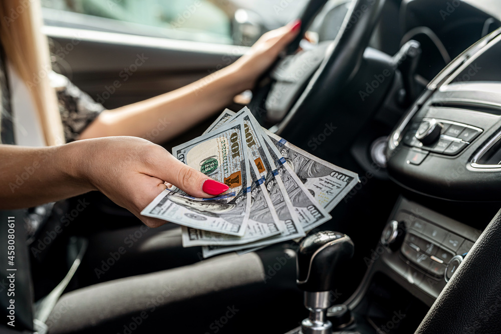 female hand counting us dollar in a car