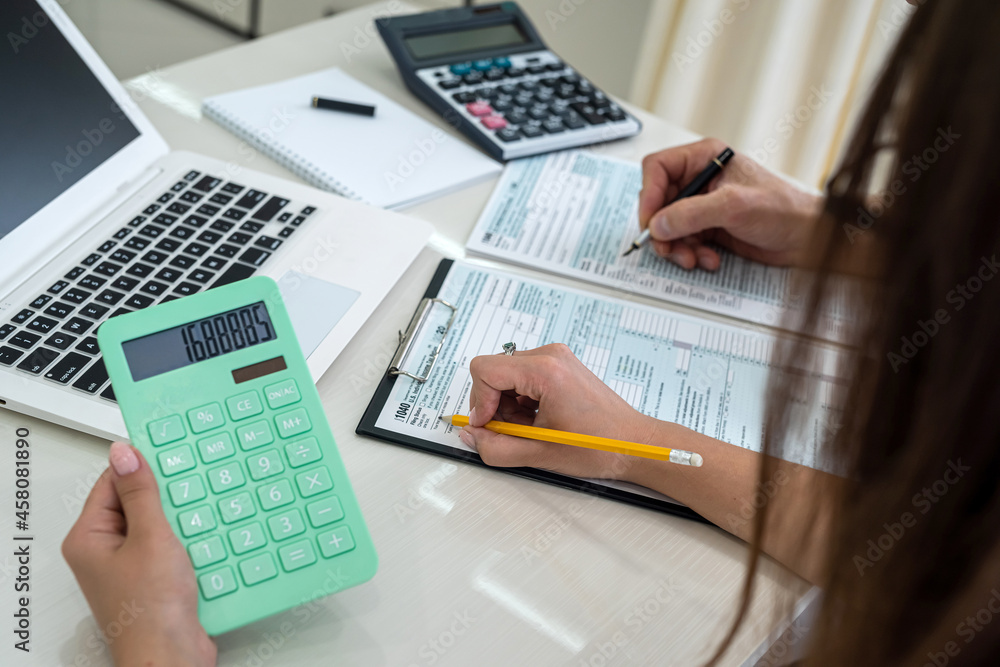 Female hands with calculator above 1040 tax form Female hands with calculator above 1040 tax form