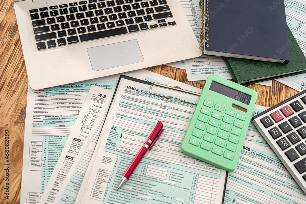 Obraz premium on a wooden table lie a laptop, American tax forms with a tablet and a pen