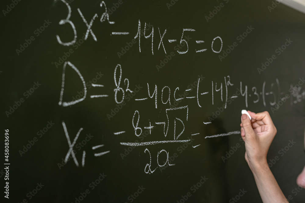 female hand writing math formulas on the classboard female hand writing math formulas on the classboard