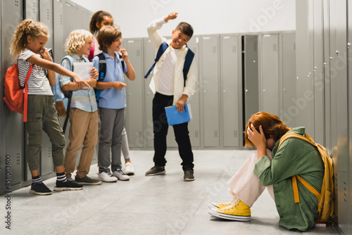 Angry cruel teenagers laughing at their classmate. Elementary school age bullying at school. Social inequality problem. Schoolchildren baiting