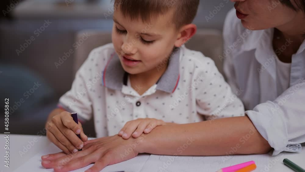 Little boy and his beautiful mother using colorful pencils and copybook for drawing during free time at home. Concept of children creativity. Little boy and his beautiful mother using colorful pencils and copybook for drawing during free time at home. Concept of children creativity.