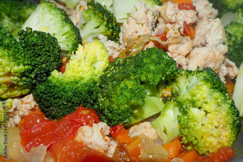 broccoli, carrots,tomatoes and red sweet peppers are cooked together with chicken meat . side view
