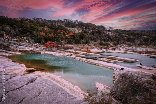 Peranales River that sometimes flows underground near LBJ Ranch in Teaas under crazy sunset sky with fall foliage and tourists. photo