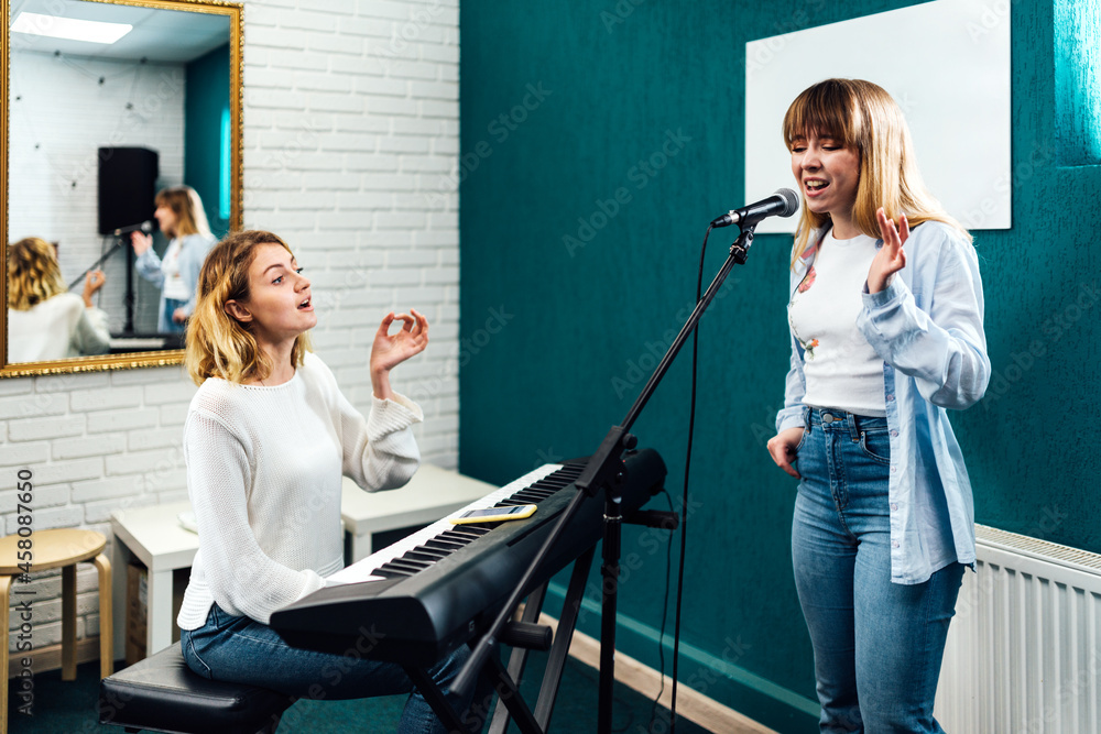 Vocal coach training her student's voice on a lesson - obrazy, fototapety, plakaty 