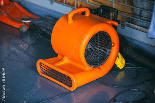 Orange blower fan machine on wet floor. Heavy Duty Industrial Portable Blower Fan on floor 
Used to reduce heat to racing cars. photo