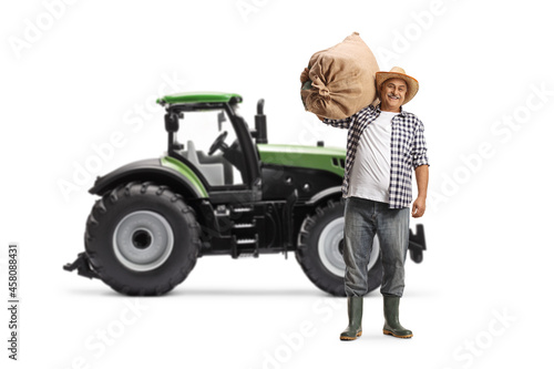 Full length portrait of a farmer carrying a sack and standing in front of a tractor