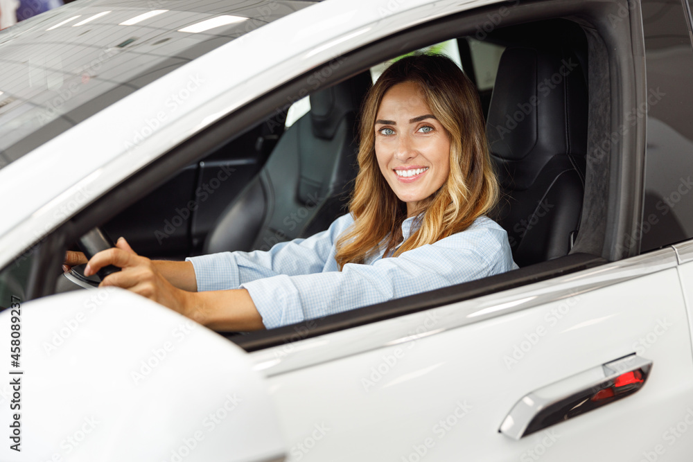 Happy woman customer buyer client in blue shirt hold put hands on steering wheel choose auto want buy new automobile in car showroom vehicle salon dealership store motor show indoor. Sales concept Happy woman customer buyer client in blue shirt hold put hands on steering wheel choose auto want buy new automobile in car showroom vehicle salon dealership store motor show indoor. Sales concept