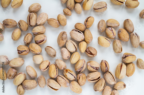 Pistachios (pistacia vera), unpeeled, in their hard shells. Nuts flat lay composition on a white background.