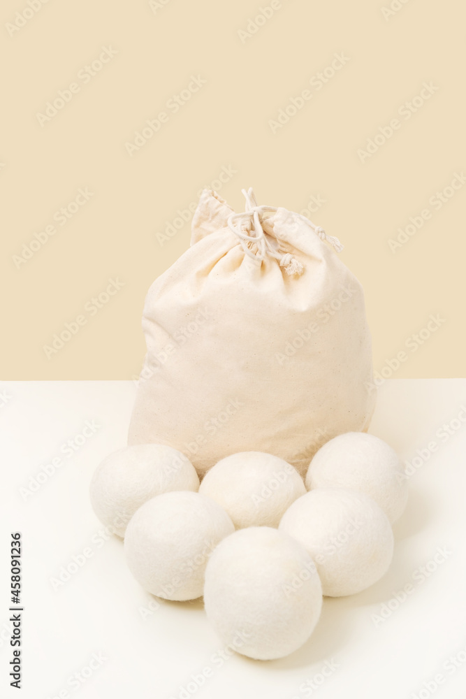 Obraz premium Wool Dryer Balls In Cotton Bag On Beige Background. Eco Friendly Laundry Supplies. Alternative Drying Of Linen. Still Life. Vertical Size